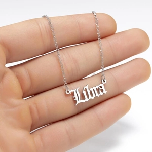 Macro shot of silver Libra zodiac pendant with gothic font on a delicate chain