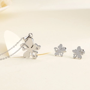 Ensemble collier et boucles d'oreilles trèfle argenté avec cristal sur fond beige