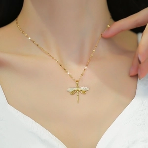 Detail of gold dragonfly pendant necklace with sparkling crystals on model collarbone