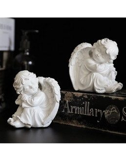 Détail de figurines d'anges en résine blanche avec plumes sur des livres vintage