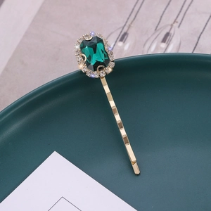 Elegant gold hair clip with a large rectangular green crystal and sparkling rhinestones