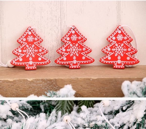 Close-up of three red wooden Christmas tree ornaments with white snowflake patterns and strings