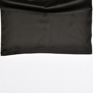 Close-up of the black satin dress hem showing fine stitching and smooth fabric texture