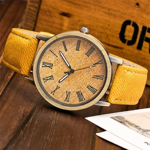 Dettaglio del cinturino in tela giallo senape e cassa in bronzo dell'orologio al quarzo