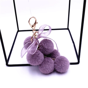 Cute purple plush grape keychain with a silk bow and golden metal clip on a white background