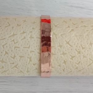 Close-up of rose gold copper magnetic bracelet with hammered texture on display stand