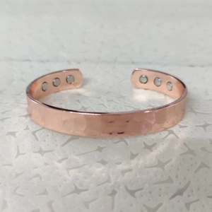 Detail view of adjustable rose gold copper bracelet featuring six healing magnets inside