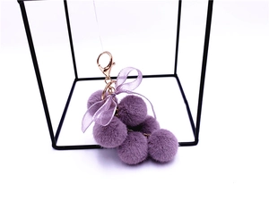 Detail of purple plush grape keychain with a lace bow and rose gold alloy hook