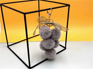 Plush grape keychain with grey faux fur pom poms and a green lace ribbon bow charm