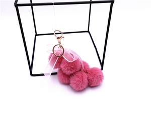 Detailed close-up of a pink plush dog keychain with a lace bow and rose gold metal clasp