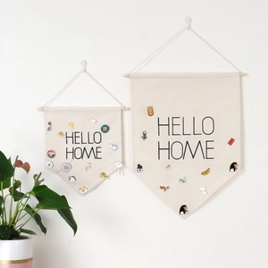 Close-up of beige canvas wall banners with Hello Home text and pin badge display