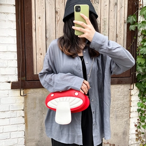 Detail of red and white mushroom shaped PU crossbody bag with slim metal chain strap