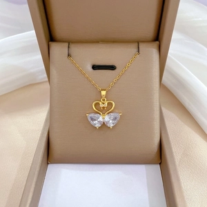 Macro detail of golden double swan heart pendant with pavé cubic zirconia in a gift box