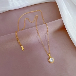 Elegant gold plated titanium necklace with round zircon pendant on soft silk background