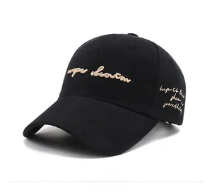 Detail view of deep black baseball cap featuring beige cursive embroidery on twill cotton