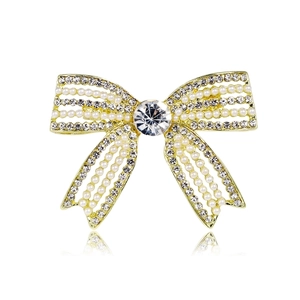 Detailed close-up of bow knot brooch with gold metal, pearls, and sparkling crystals