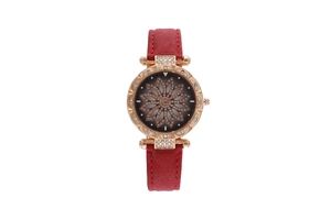 Detail of rose gold watch case with crystal accents and flower pattern on a red strap