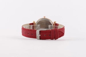 Detail of red suede leather watch strap with rose gold case and silver buckle closure