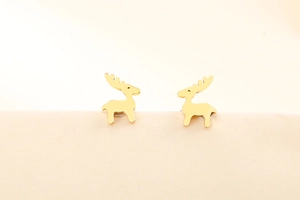 Macro di orecchini a lobo a forma di renna dorata su sfondo beige minimalista