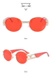 Détail de lunettes de soleil ovales avec verres rouges et branches dorées ajourées