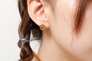 Gros plan d'une boucle d'oreille trèfle dorée portée avec des détails précis