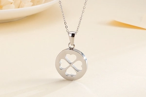 Détail du collier en acier argenté avec pendentif rond à motif trèfle ajouré
