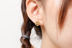 Close-up of model wearing gold tree of life stud earrings with hollow design