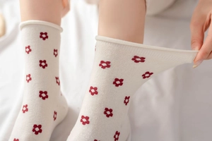 Detail of white cotton socks featuring red heart patterns with a flexible rolled top