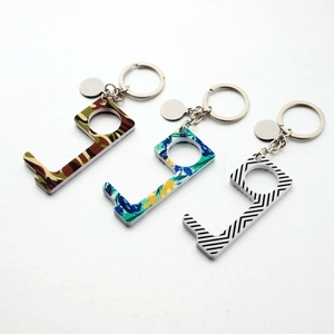 Three patterned acrylic EDC keychains in camo, floral, and stripes on white background