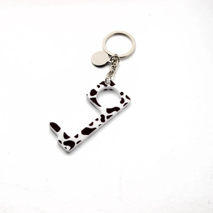 Detail view of cow print acrylic no-touch key tool with metal keyring and blank tag
