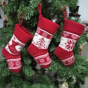 Three knitted Christmas stockings with reindeer, tree, and snowflake hanging on a tree