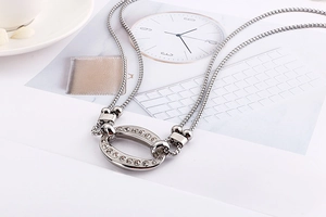 Detail of silver double-layered chain necklace with a crystal-encrusted oval pendant