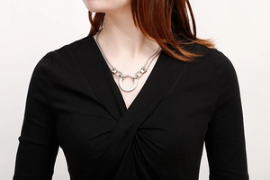 Close-up of a double-layered silver necklace with a sparkling round rhinestone pendant