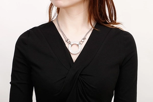 Detail of a silver-tone double-layer necklace with a circular pendant on a model