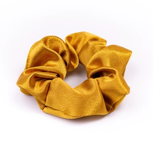 Close-up of a high-quality golden satin scrunchie with elegant pleated fabric texture