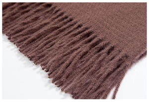 Close-up of soft dark brown fringe tassels and texture on a knitted winter scarf