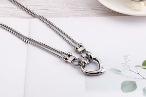 Detail of silver double-layered necklace with an asymmetric heart pendant on a box chain
