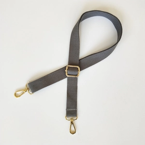 Détail de la bandoulière en toile gris foncé avec boucles et mousquetons dorés