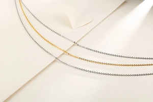 Detailed shot of three minimalist stainless steel cross chains in silver and gold tones
