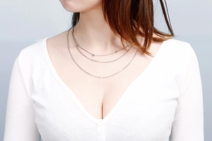 Detail shot of a triple-layered silver chain necklace with small beads on a female model