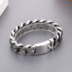 Detailed view of silver punk style Cuban link bracelet with textured rivets on grey background