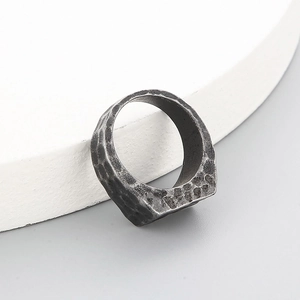 Detail of vintage rectangular stainless steel ring with hammered texture on white stand