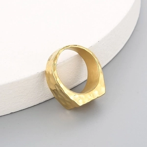 Detailed close-up of golden wide-band ring with vintage hammered metal texture finish