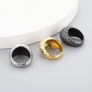 Detailed view of wide band rings with hammered texture in silver, gold, and vintage black