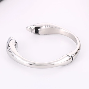 Detailed close-up of polished silver stainless steel cuff with double shark head motifs