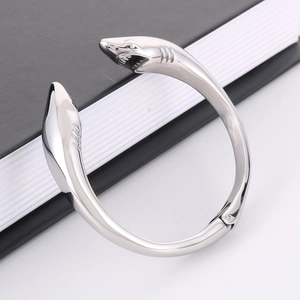 Polished stainless steel cuff bracelet featuring dual shark head design on a black book