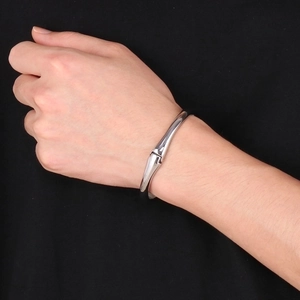 Close-up of a silver stainless steel double dolphin open cuff bracelet on a wrist