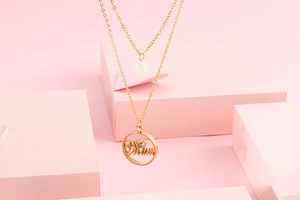 Close-up of gold double-layer necklace with a white bead and a circular Mum pendant
