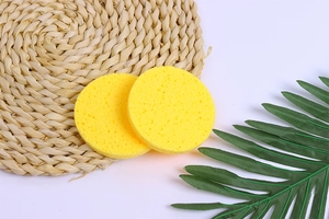Detailed view of two yellow wood pulp facial sponges with natural porous texture