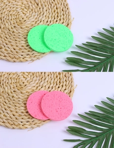 Detailed close-up of pink and green natural wood pulp cellulose facial sponges on a mat